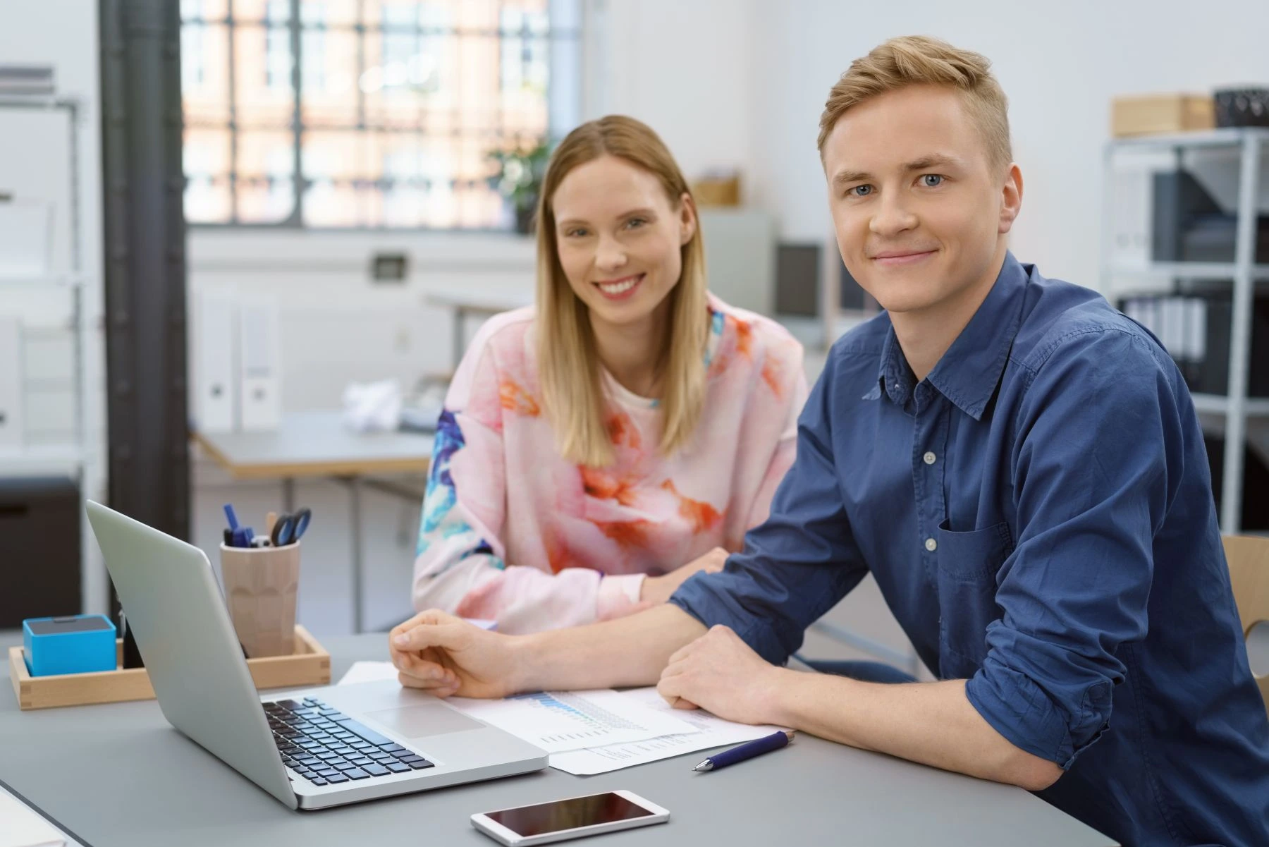 2 personen an einem schreibtisch mit monitor