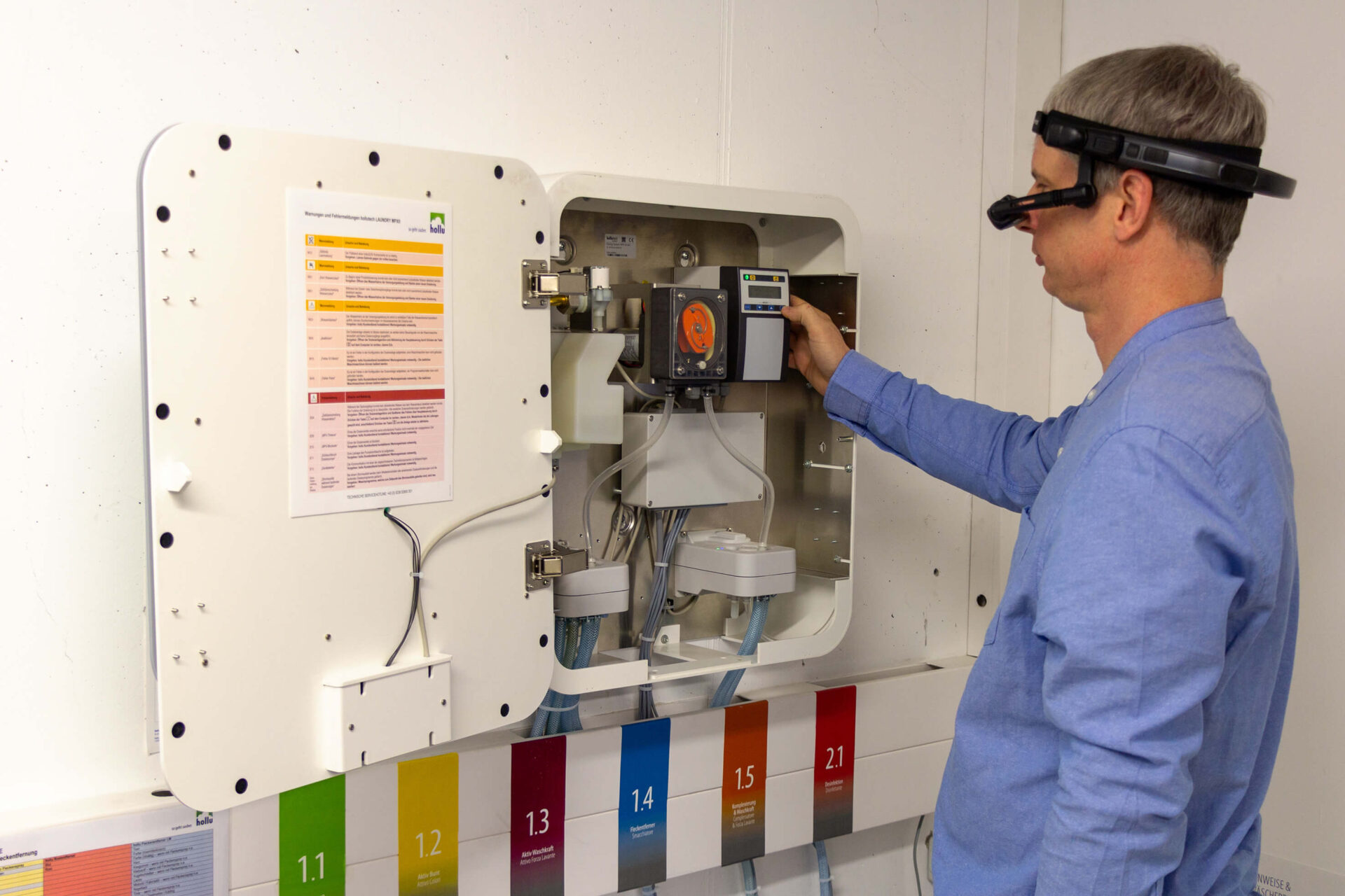 Mann in blauem Hemd mit Datenbrille, der an einer Dosieranlage Servicearbeiten verrichtet