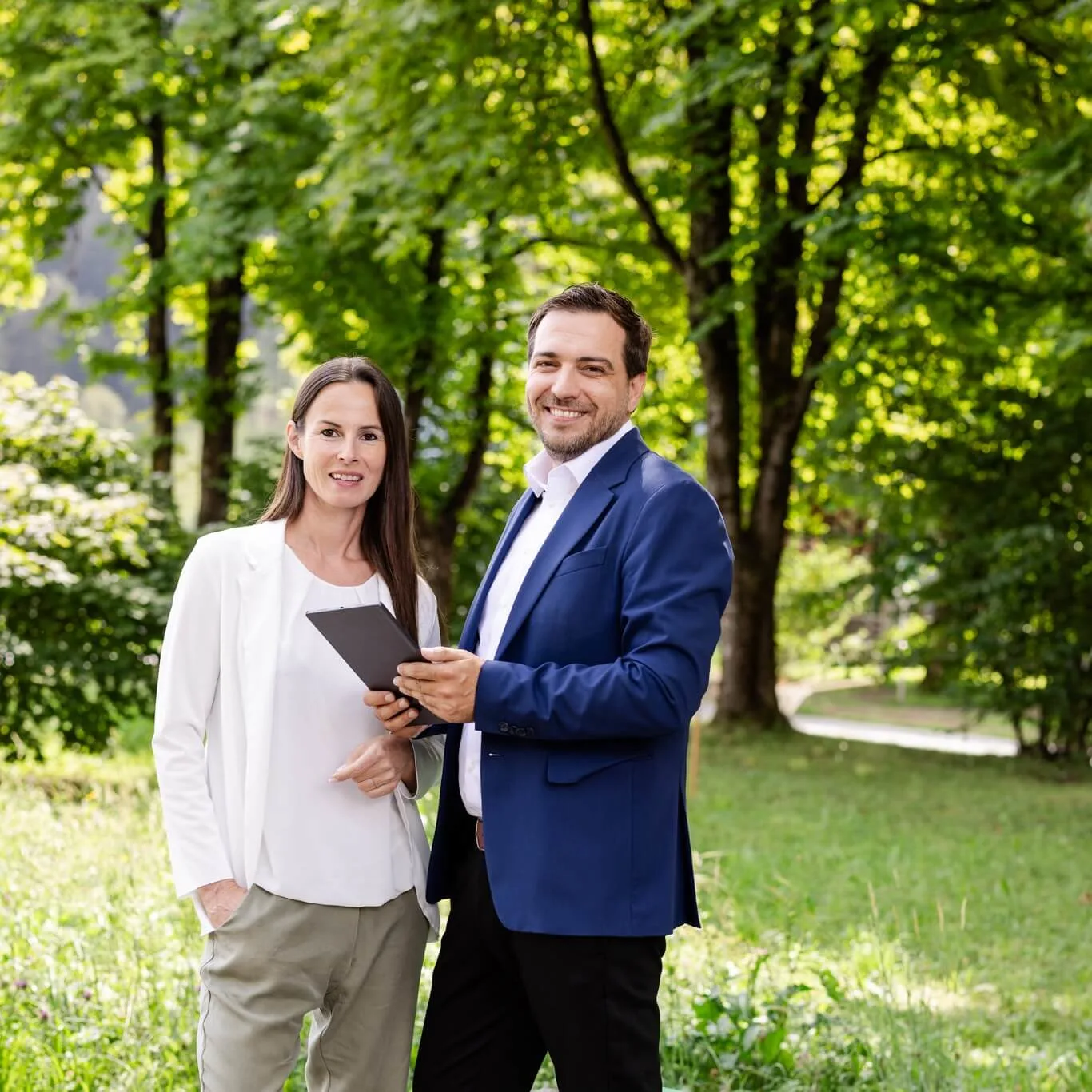 2 personen in einem garten, eine hat ein tablet