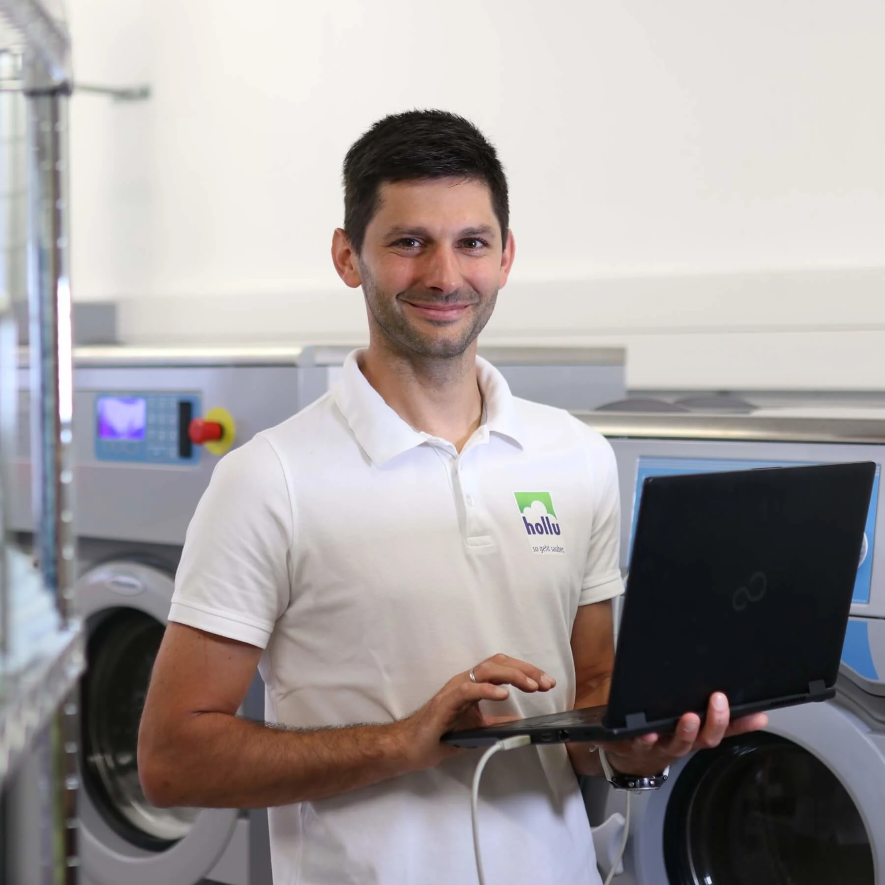 eine person mit einem laptop vor einer waschmaschine