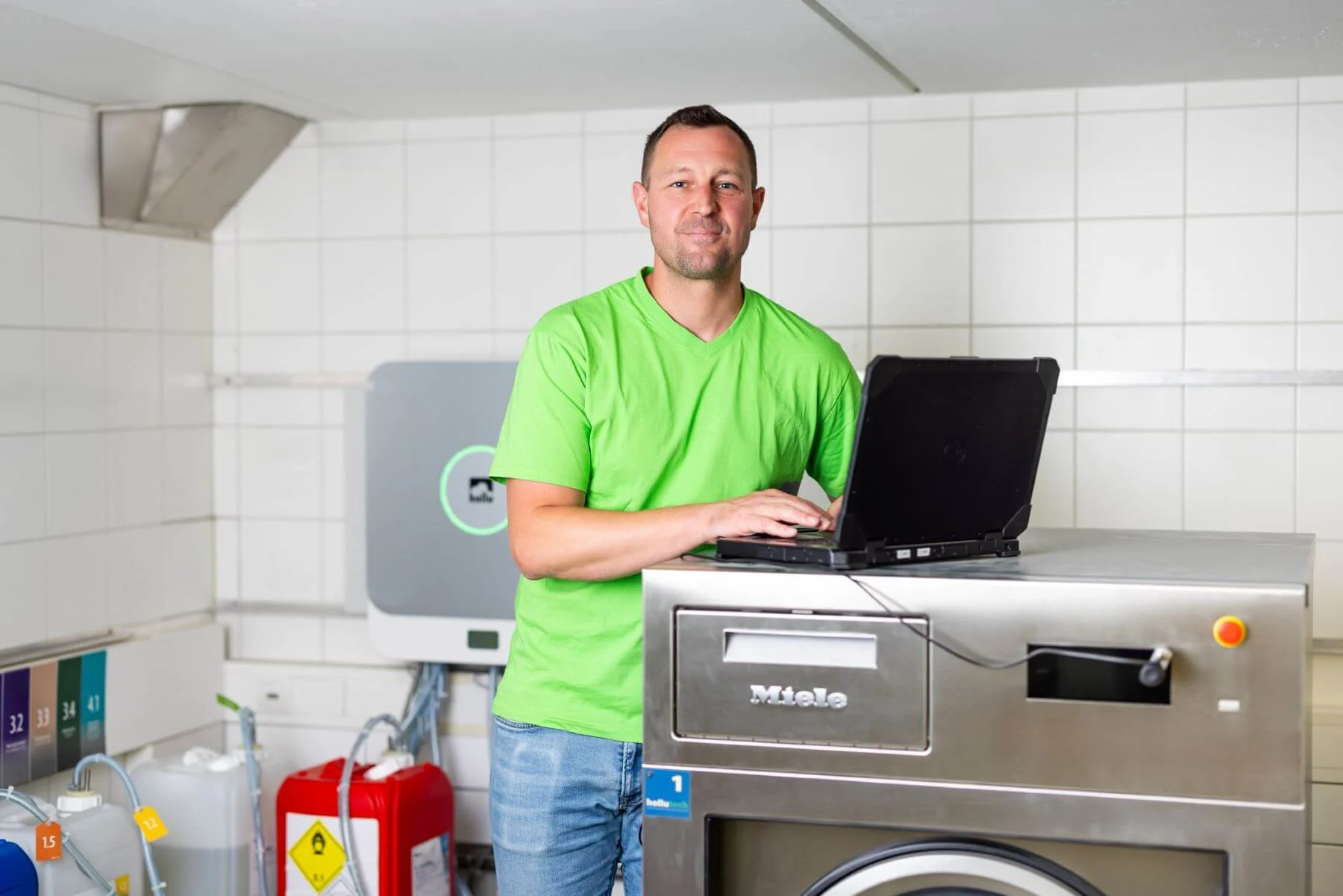 eine person mit einem laptop vor einer waschmaschine