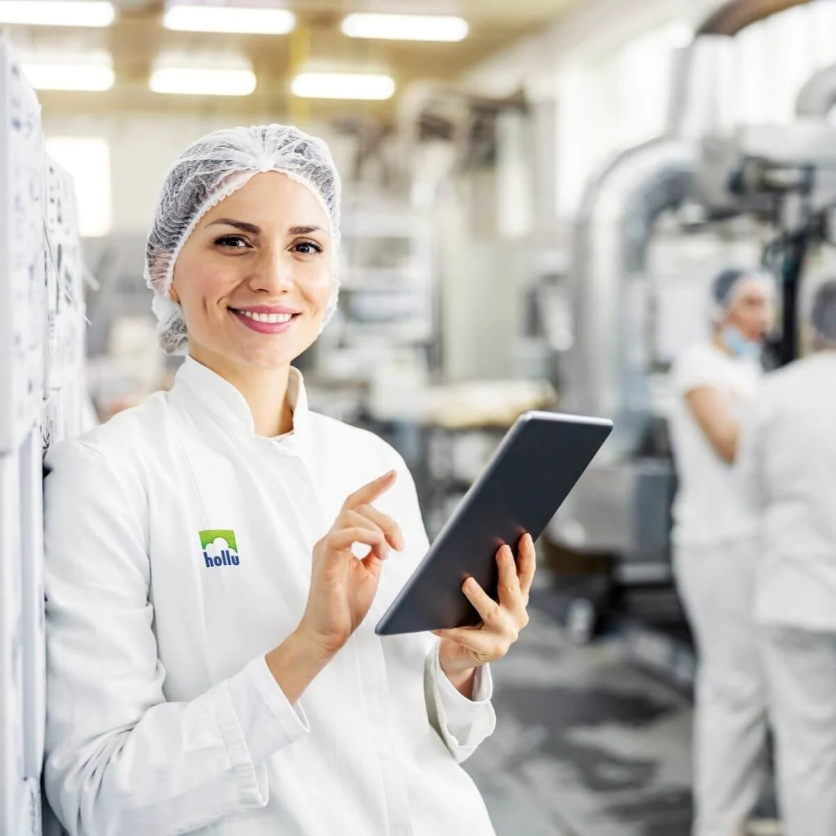 mehrere Personen mit Haarnetz und Tablet in einer Produktion
