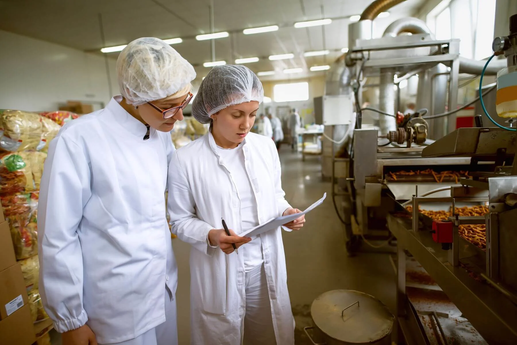 2 Personen mit Haarnetz und Klemmbrett in einer Produktion