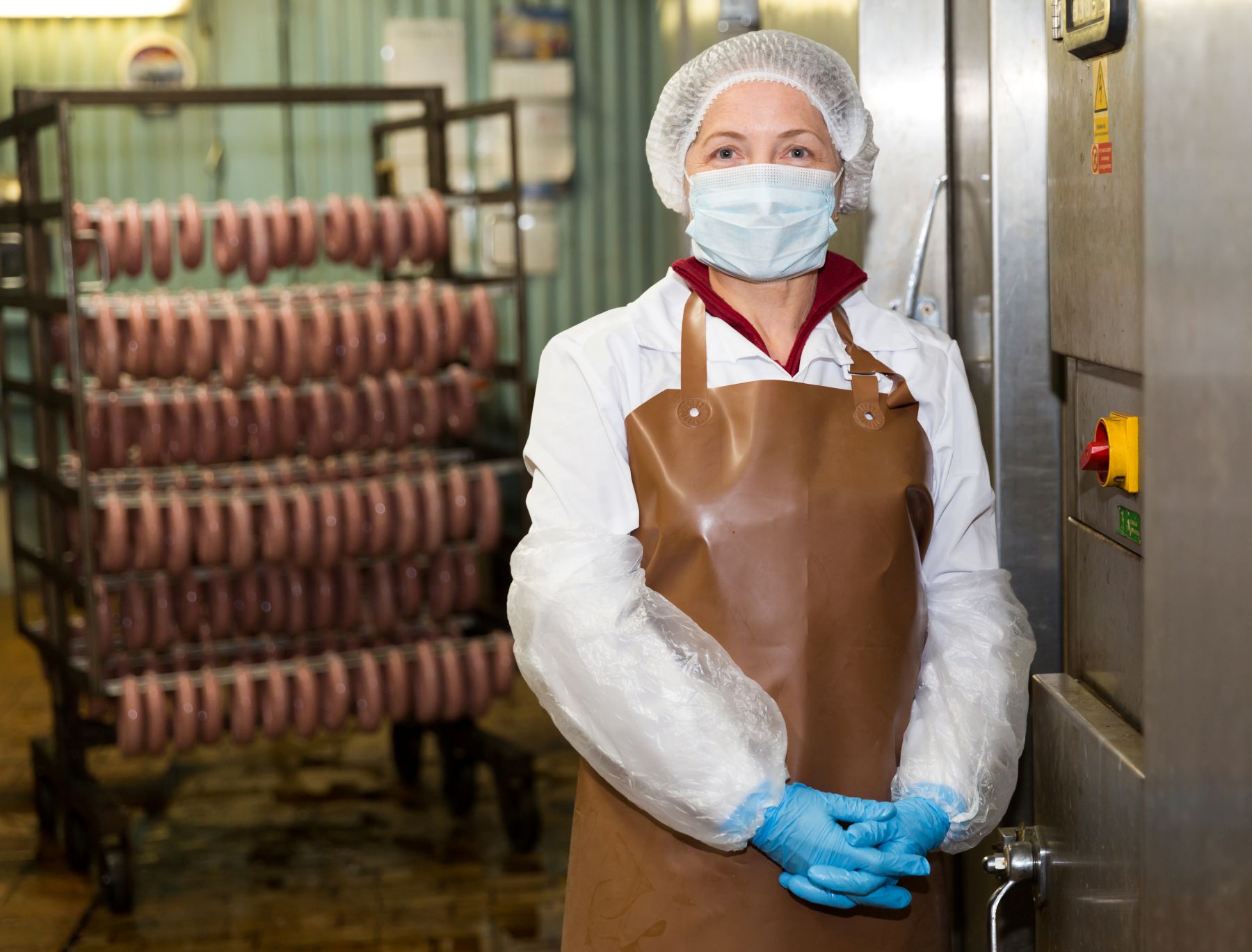 Eine Person mit Mundschutz in Wurstproduktion