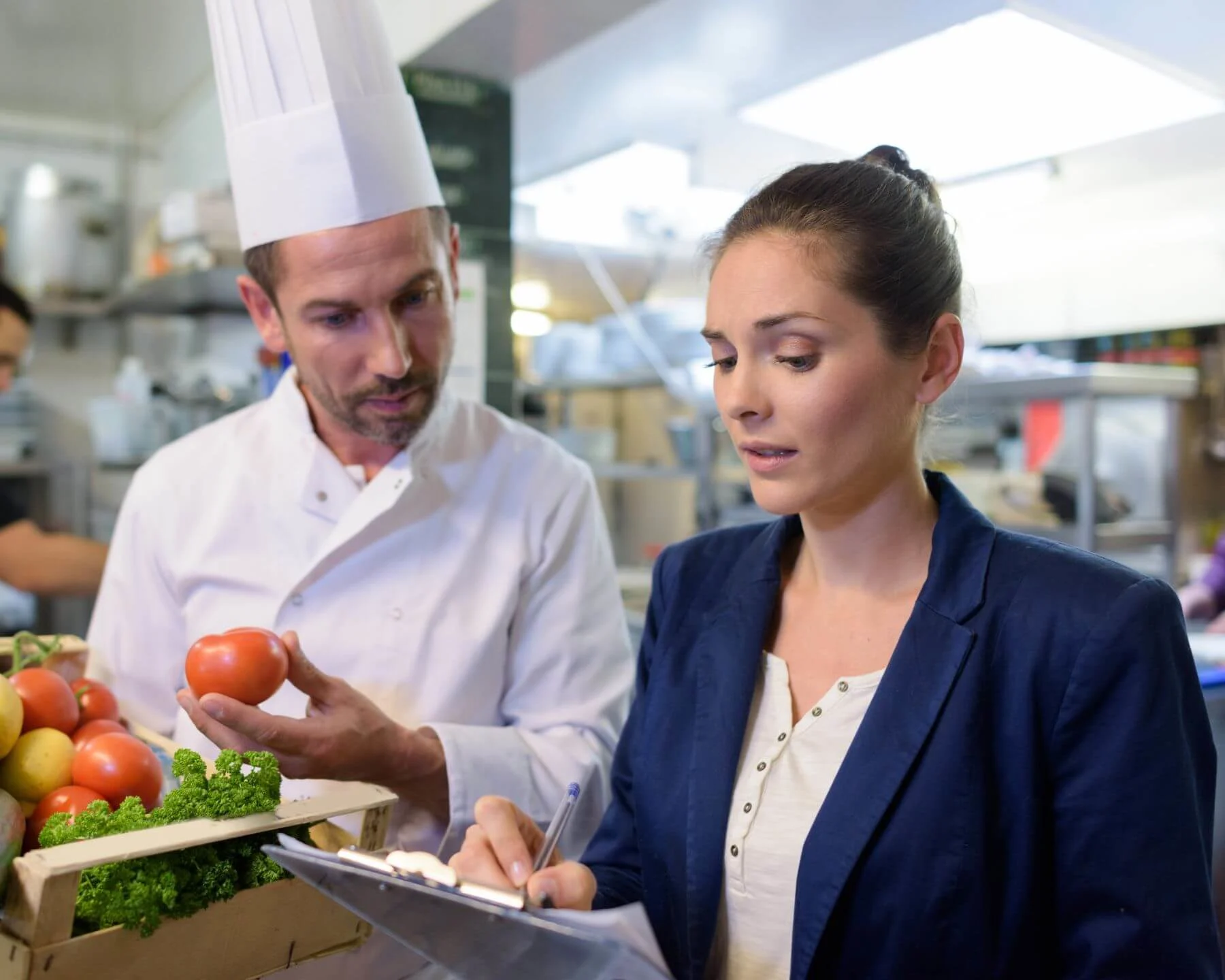 2 personen mit lebensmittel und clipboard in einer küche