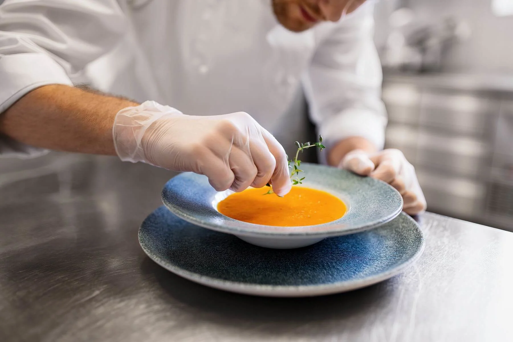 eine rperson richtet eine orange suppe in einem Teller an