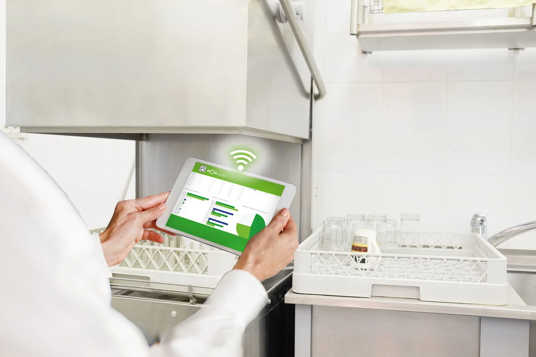 eine person mit einem tablet vor einer spülmaschine