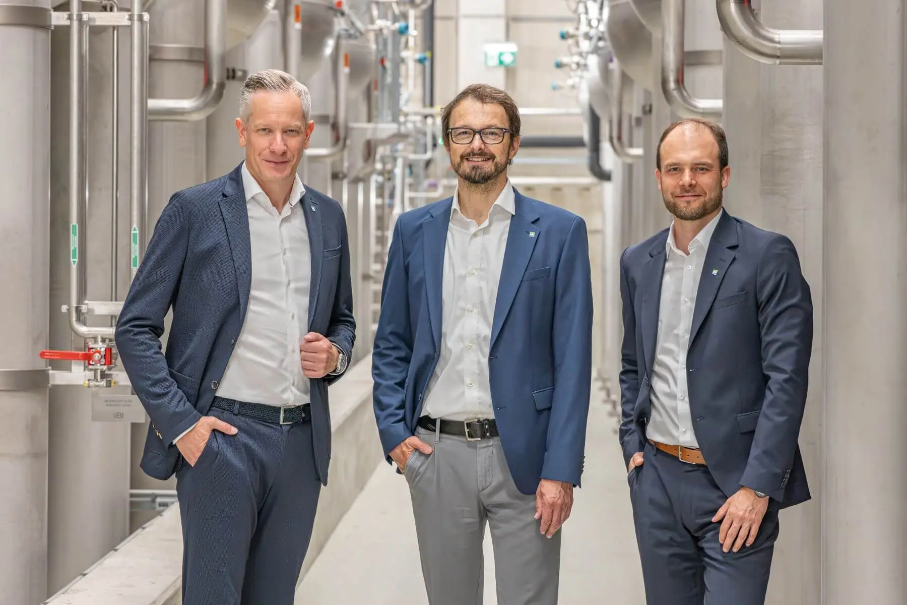 3 Personen im Anzug vor Tanks